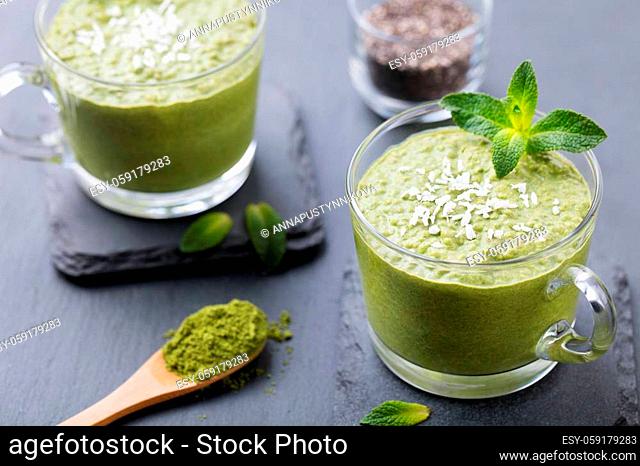 Matcha green tea chia seed pudding, dessert with fresh mint and coconut on a black slate background. Healthy breakfast