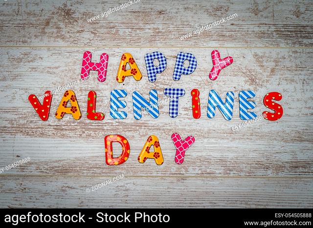 Happy Valentines Day made of single colourful letters in lines on white painted vintage oak panels