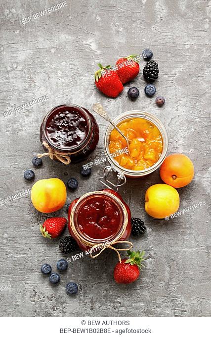 Strawberry, blueberry and peach jams in glass jars. Party dessert