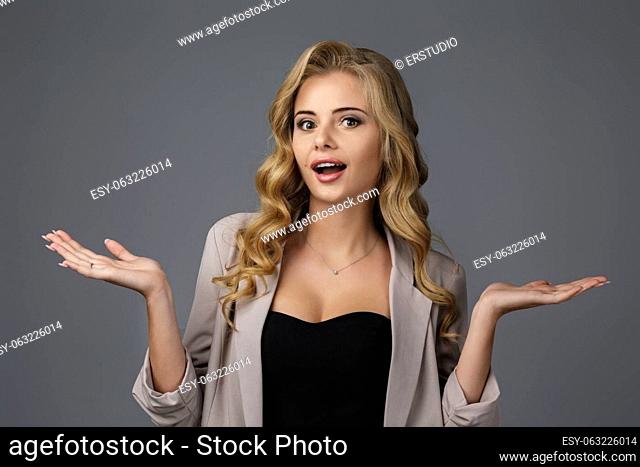 Portrait of young surprised beautiful woman with shocked facial expression on gray background