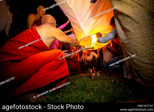 Bangladesh - October 13, 2019: A Buddhist monk with his disciples trying to fly a paper lantern at Ujani Para Buddhist Temple in Bandarban, Bangladesh