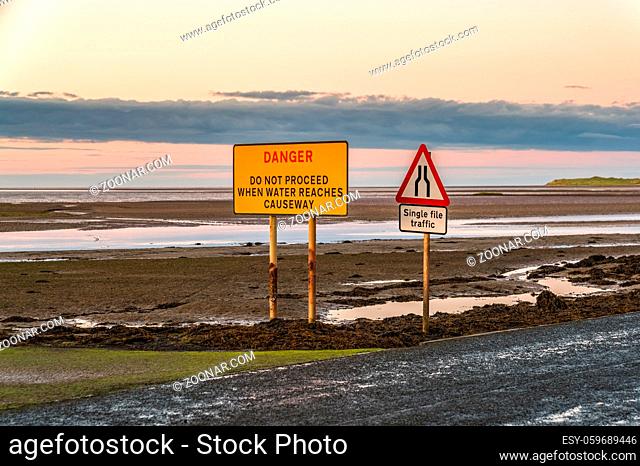 Sign: Single File Traffic, Danger do not proceed when water reaches causeway, seen on the road between Beal and Holy Island in Northumberland, England, UK