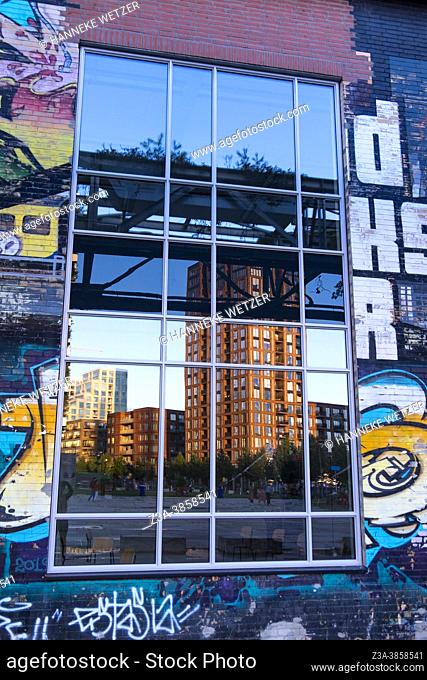 Reflection of modern architecture in the window of a building with graffiti, Strijp-S, Eindhoven, the Netherlands