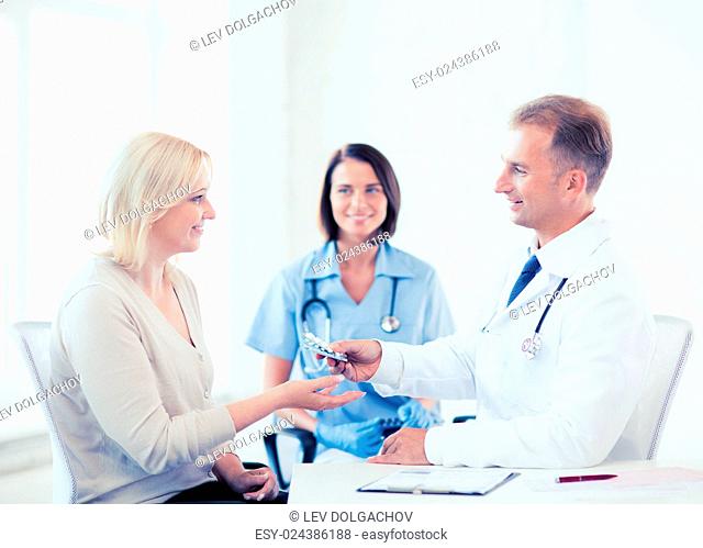 healthcare and medical concept - doctor giving tablets to patient in hospital