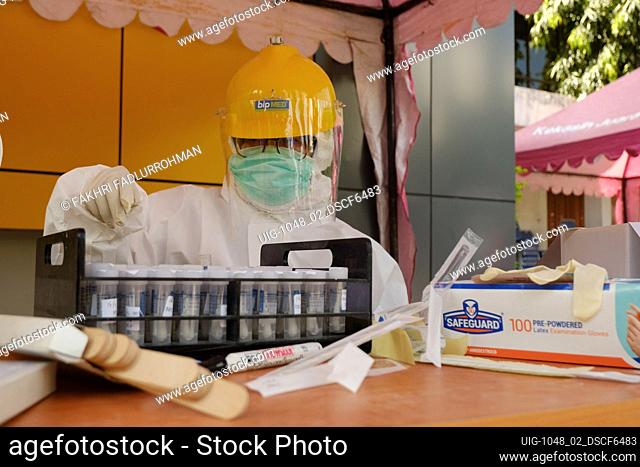 A health worker wearing protective suit as a preventive measure collect a tube swab sample in Bandung, West Java, Indonesia, May 16, 2020