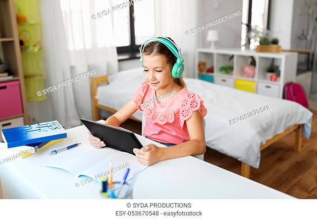 girl in headphones with tablet computer at home