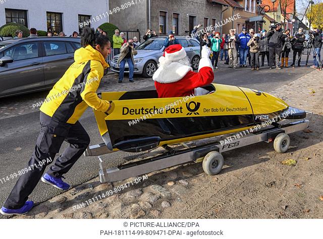 14 November 2018, Brandenburg, Himmelpfort: Mariama Jamanka, 2018 Olympic champion in the two-man bob, pushes Santa Claus in a yellow bobsled to the Christmas...