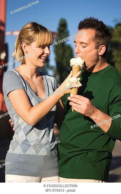 Cheerful couple with ice cream cones out of doors