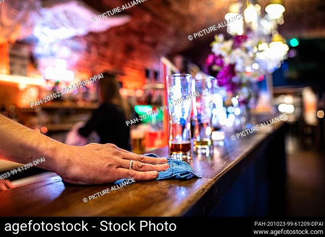 23 October 2020, North Rhine-Westphalia, Warendorf: Shortly before closing time, a waitress wipes the counter of the Warendorf Bar #one next to two empty...