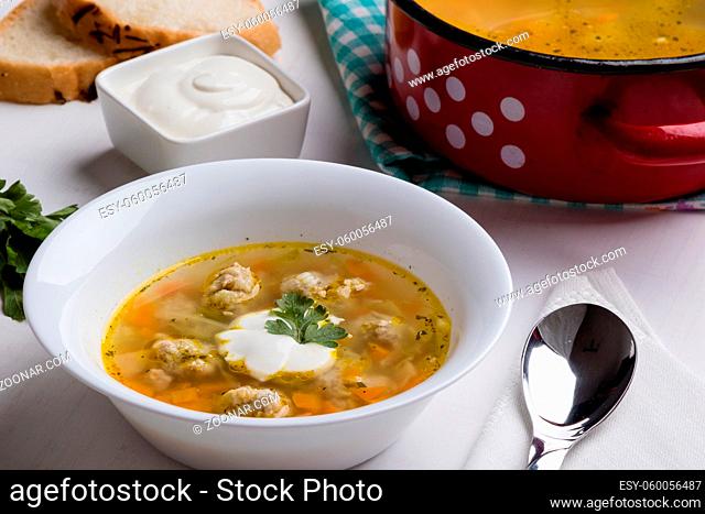 vegetable soup with meatballs on white table in bowl