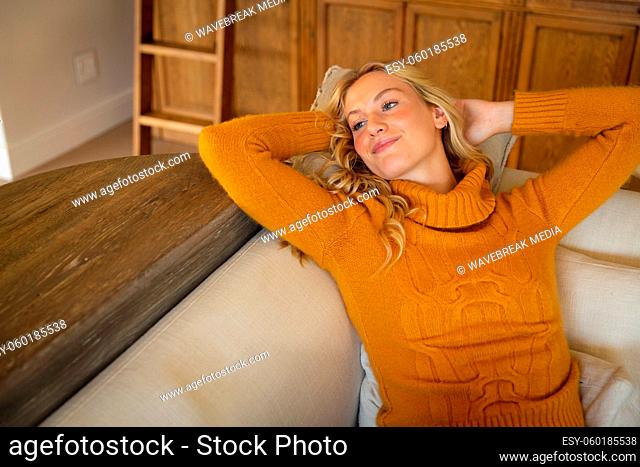 Portrait of happy caucasian woman lying back on couch relaxing in living room, smiling