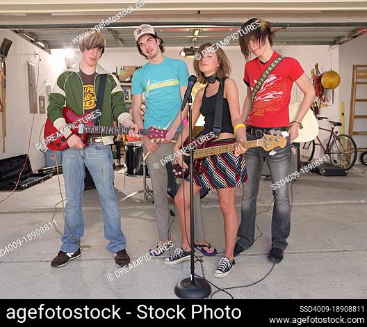 Group portrait of Friends in garage band after practicing in driveway in front of home