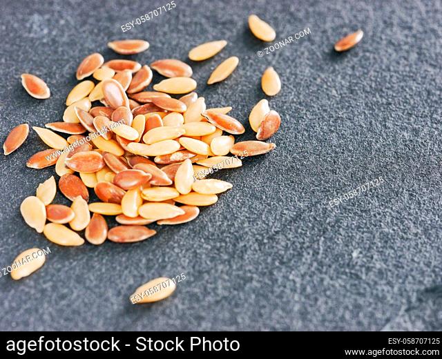 Golden and brown flax seed on gray slate background with copy space