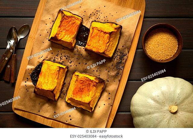 Baked pumkin pieces with caramelized sugar on top, a traditional autumn snack in Hungary, photographed overhead on dark wood with natural light