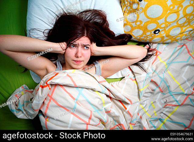 Tired woman sleeping on a bed at home. Noisy neighbors, stress, headache, insomnia concept