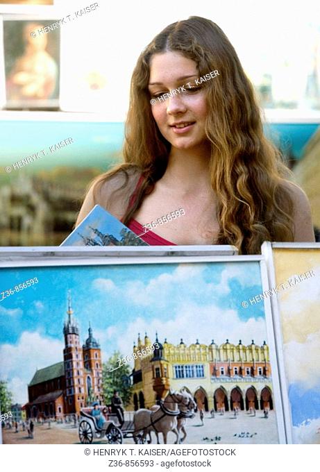 Poland Krakow, young woman by a paintings