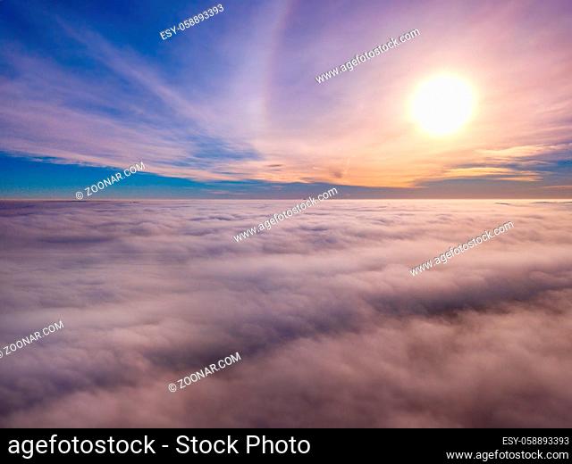 Aerial photo above the fog or white clouds with shining sun. Beautiful sunrise cloudy sky from aerial view. Above clouds from airplane window or drone