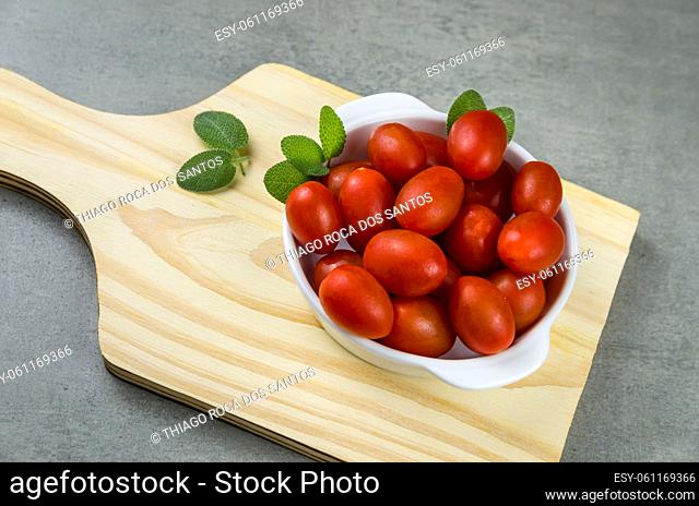 Wooden board with cherry tomatoes on gray background. culinary background