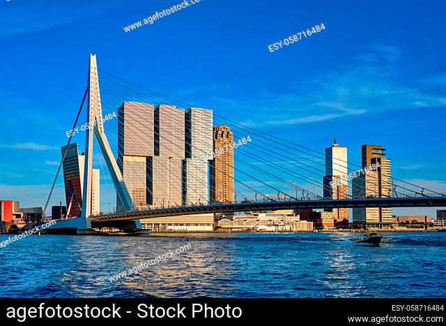 Erasmus bridge over Nieuwe Maas river on sunset with speed boat passing under the bridge. Rotterdam, Netherlands