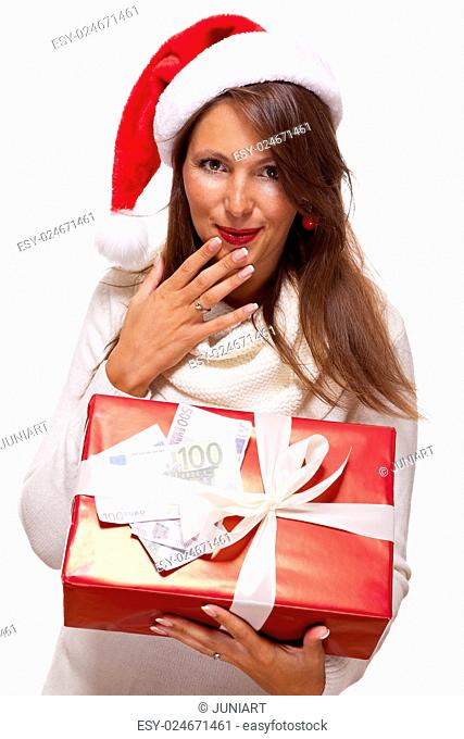 Vivacious beautiful young woman wearing a Santa hat with a large red Christmas gift and money, conceptual of successful Xmas shopping and payment, on white