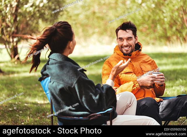 happy couple drinking tea at tent campsite