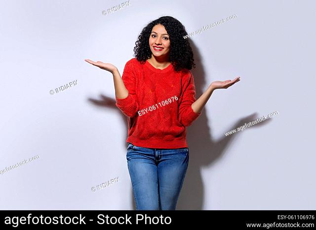 Young woman in red sweater posing with raising her arms