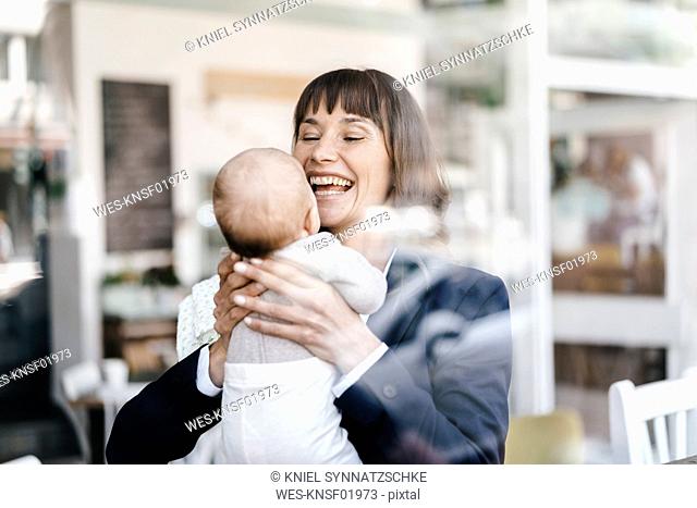 Businesswoman in cafe holding her baby