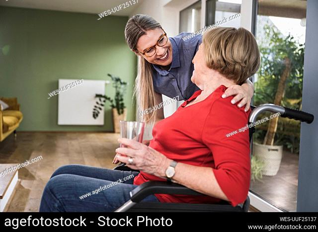 Care assistant smiling at disabled patient in wheelchair