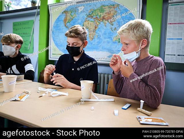 05 August 2021, Hamburg: Arjen (r-l), York and other pupils of class 6a at the Goethe-Gymnasium in Hamburg-Lurup, take a Corona quick test in the classroom on...