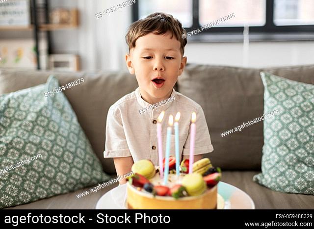 happy little boy blowing candles on birthday cake