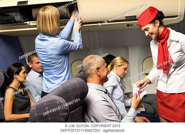 Air stewardess check passenger ticket in airplane cabin smiling