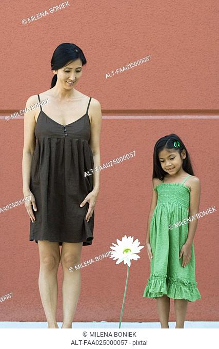 Girl and woman looking down at tall flower