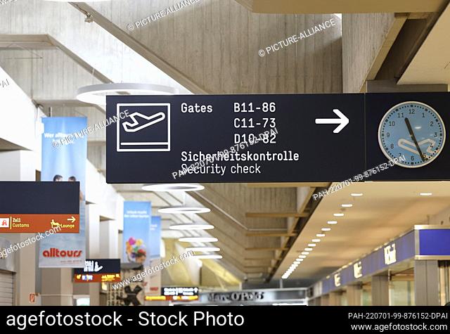 30 June 2022, North Rhine-Westphalia, Köln/Bonn: A sign indicates the security check at Cologne/Bonn Airport, before which air travelers wait in a line of...