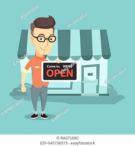 Friendly caucasian shop owner holding a signboard with the text open. Shop owner standing in front of small store. Man inviting to come in his shop