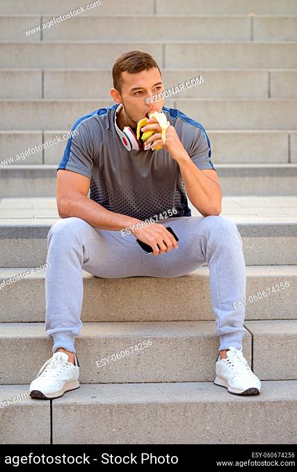 Eating banana fruit runner young man portrait format sports training fitness outdoor