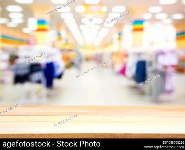Wooden board empty table in front of blurred background. Perspective light wood over blur in kids wear store - can be used for display or montage your products