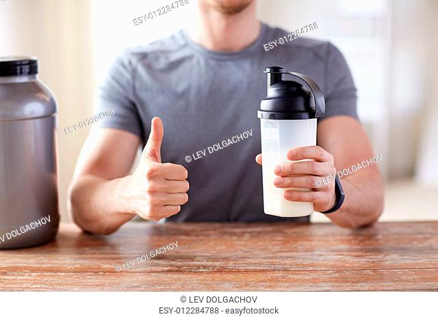 sport, fitness, healthy lifestyle and people concept - close up of man in fitness bracelet with protein shake bottle showing thumbs up