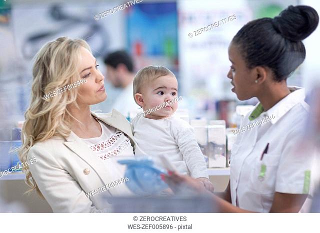 Pharmacist assisting client with baby in drugstore