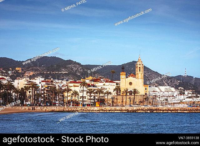 Beachfront by Sitges town with Sant Bartomeu i Santa Tecla church in the distance, Catalonia, Spain, Europe