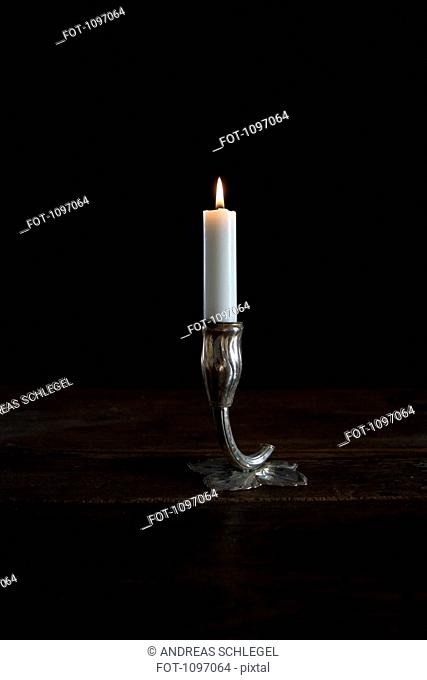 A lit candle in a silver candlestick holder