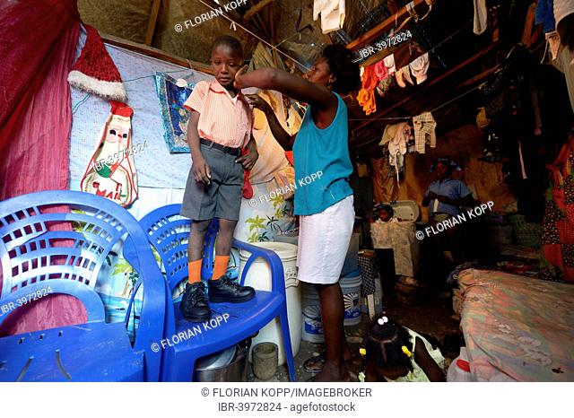 Woman dressing her son, 7 years, for his first day of school, Camp Icare for earthquake refugees, Fort National, Port-au-Prince, Haiti