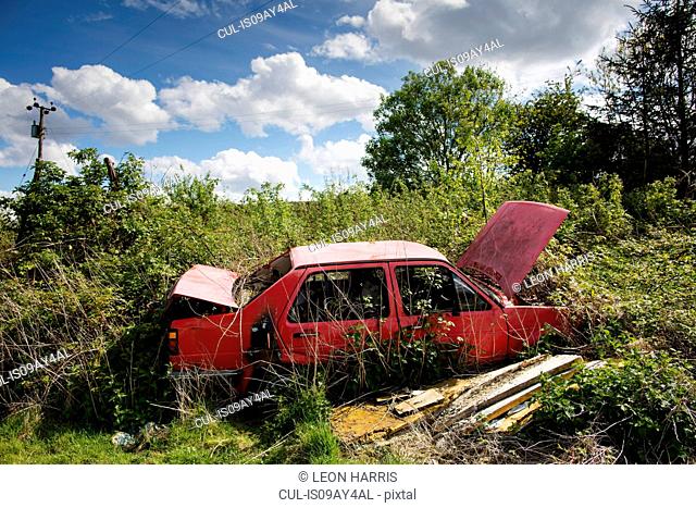 Abandoned open red car on wasteland