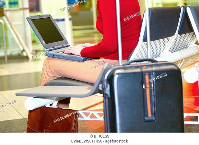 businesswoman working on laptop in the waiting area of an airport