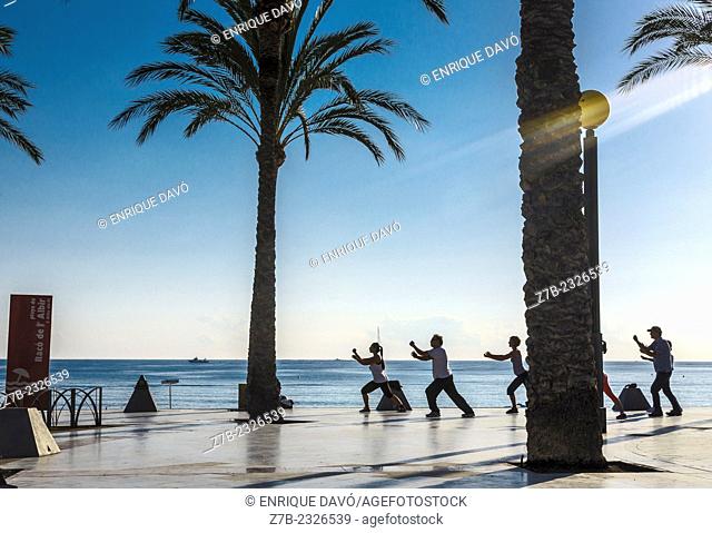 View of a persons practising Tai Chi on Albir beach, Alicante province, Spain