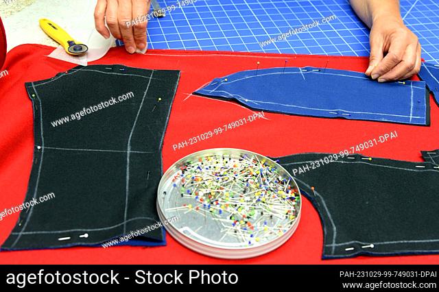 24 October 2023, Thuringia, Altenburg: At Hut und Kostüm GmbH, ladies' tailor Peggy Zimny prepares fabric parts for a uniform