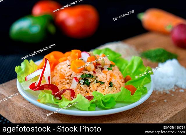 Dish with rice with vegetables, decorated with carrot and radish slices and chili strips