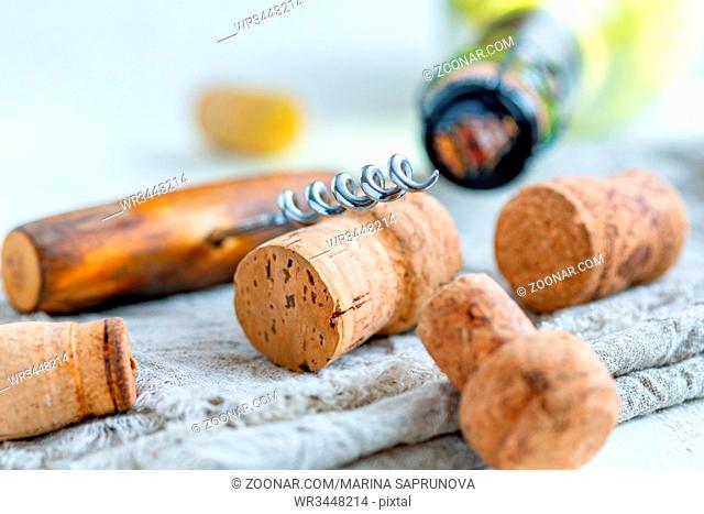 Old corkscrew and wine corks on old linen canvas, selective focus