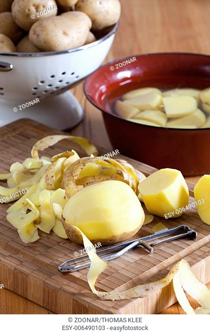 Raw potatoes and a potato peeler