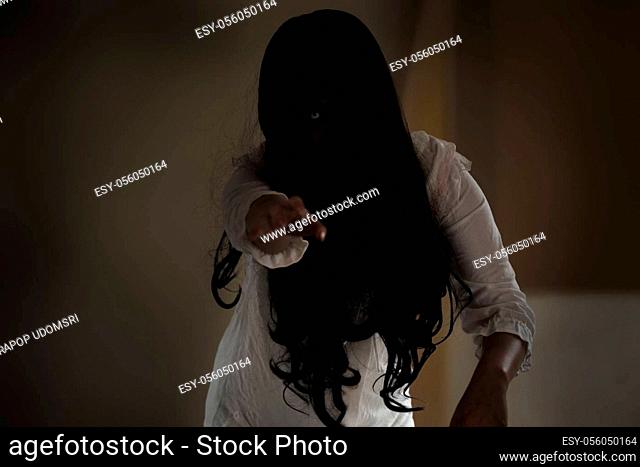 Female zombie in blood. Asian Woman ghost with blood. Horror scary fear in house dark tone raise hand and reach out. Closeup hair covering the face her eye...
