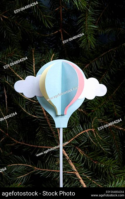 a paper hot-air balloon, initially a cake decoration, flying up from a fir-tree forest. A poetic illustration of freedom